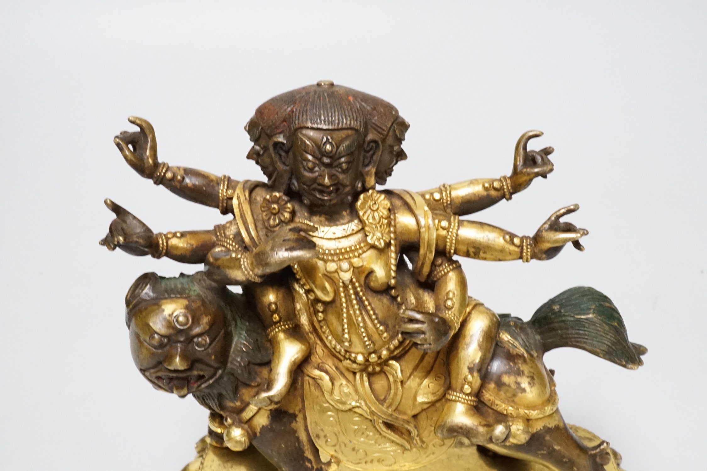 A Sino-Tibetan gilt bronze group of a deity on lionback, 15cm wide